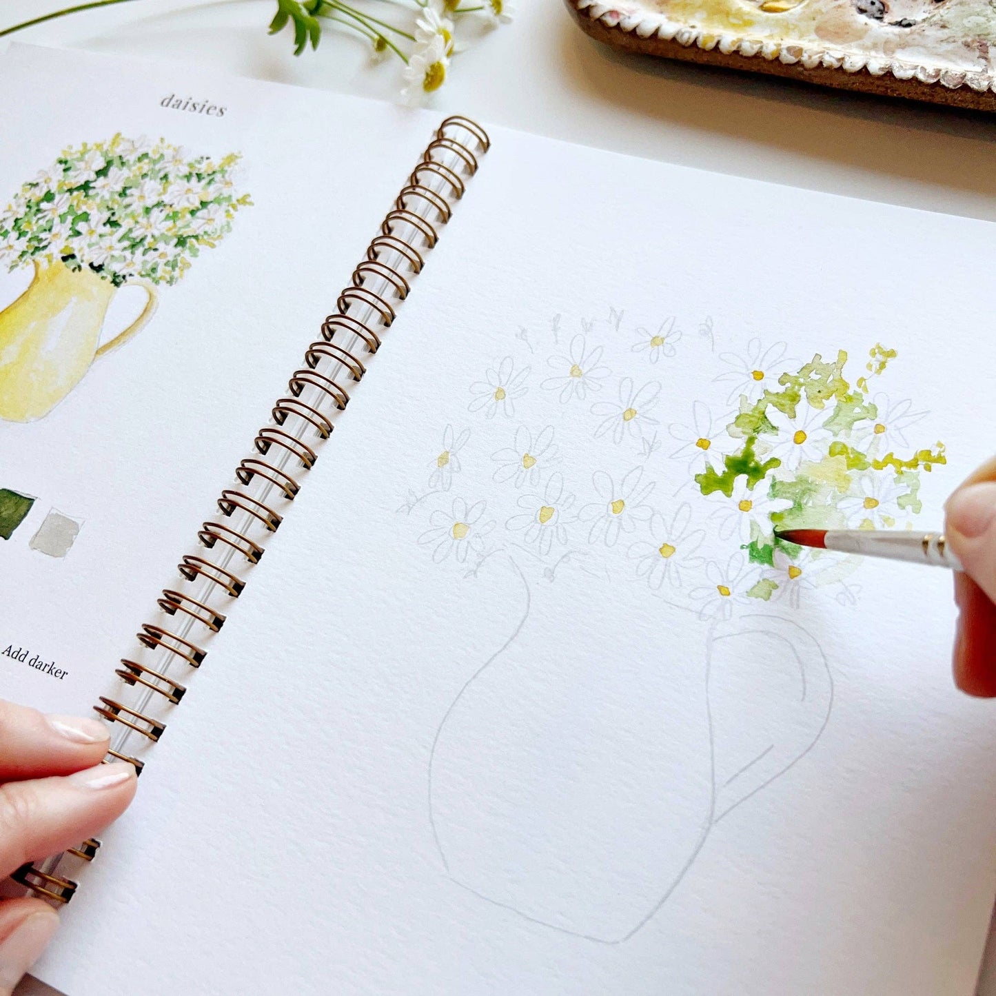 Person drawing flowers in a notebook with a pen
