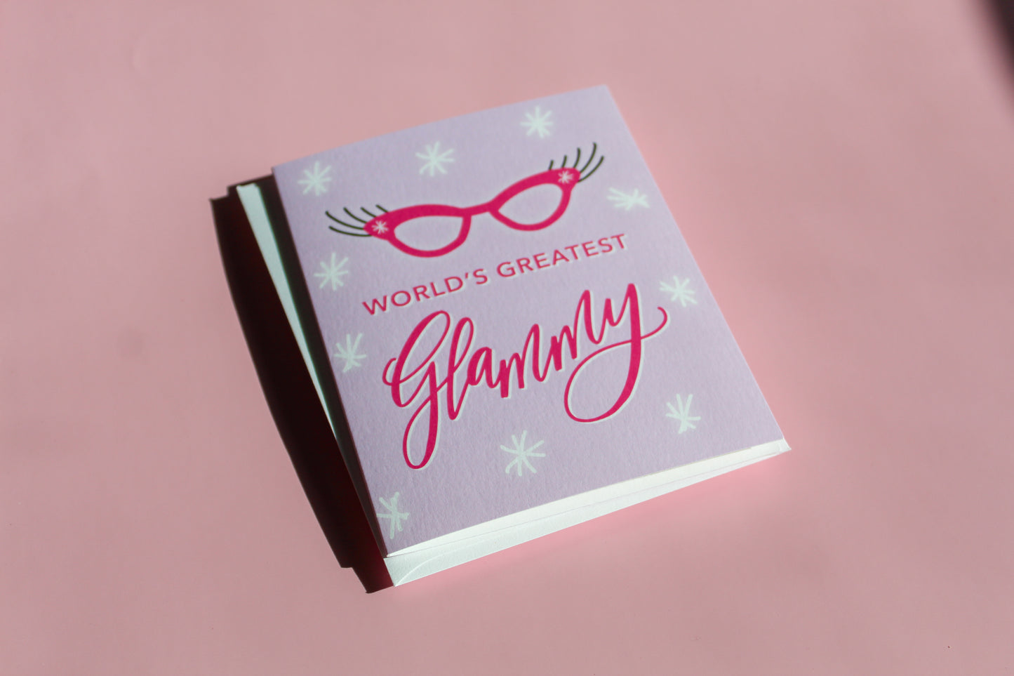 "World's Greatest Glammy" greeting card features hand drawn cat eye glasses with big lashes on a purple background