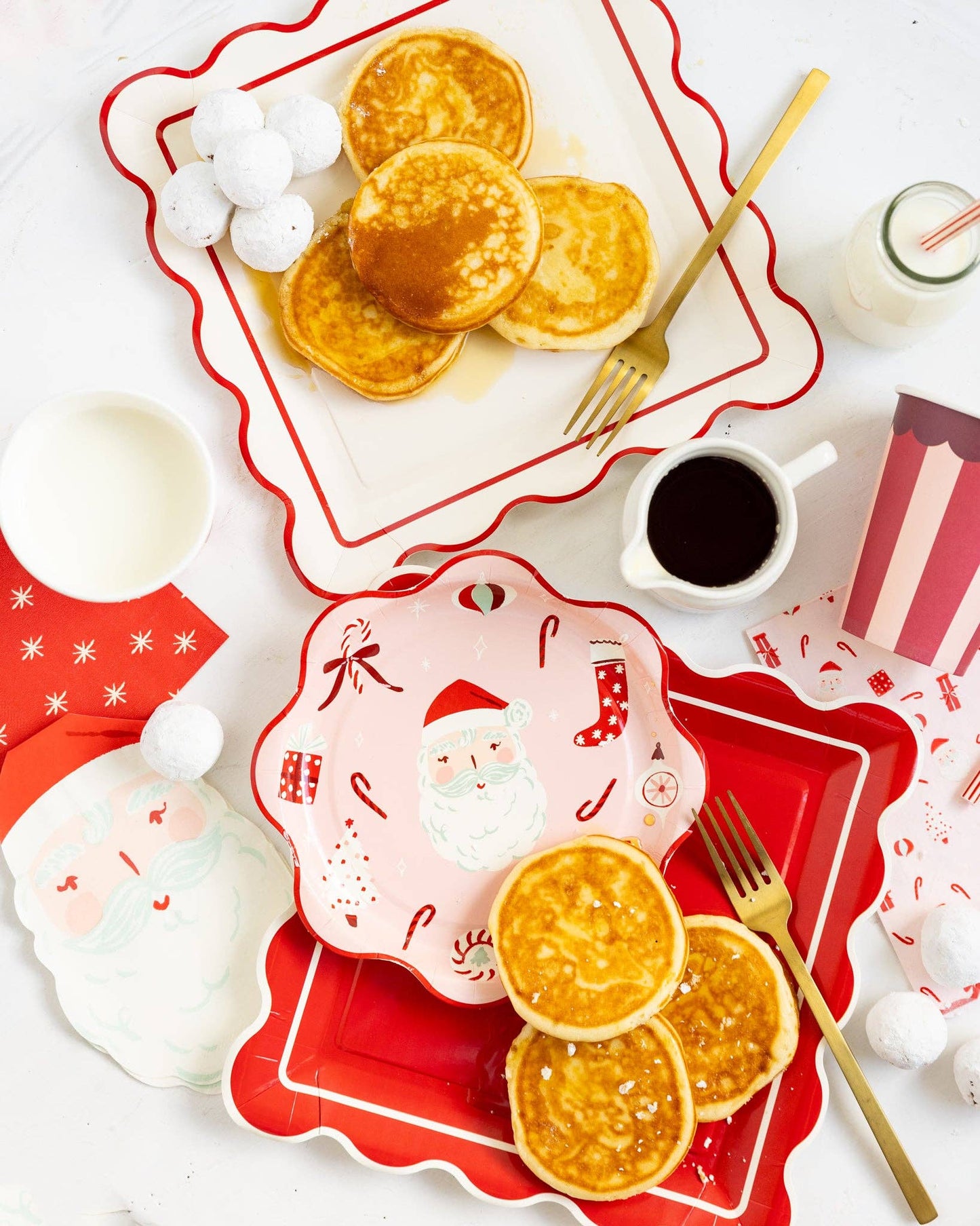 Breakfast setting with pancakes on red and white plates, including a Santa Claus design.