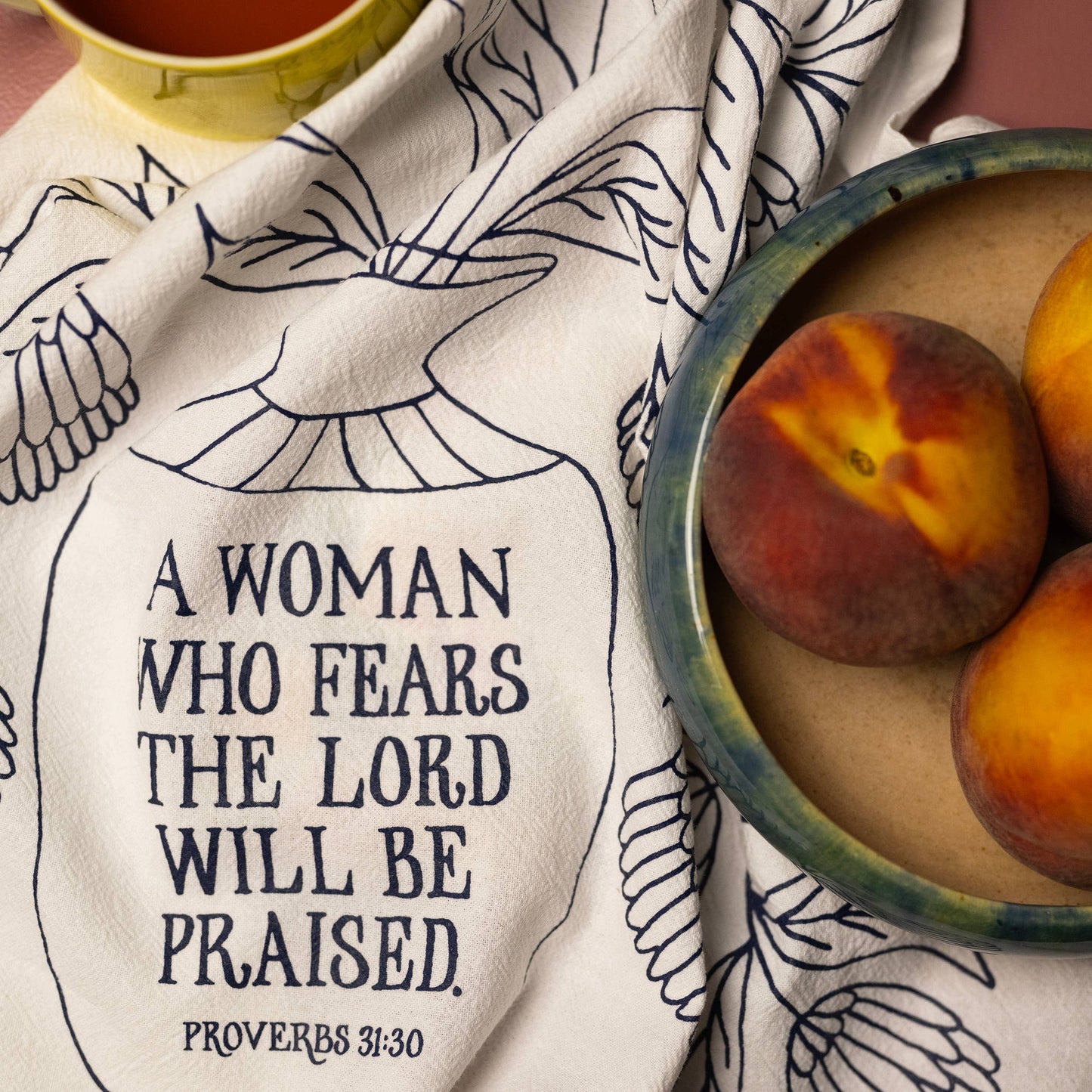 Faith-based cotton tea towel styled with peaches and coffee cup for gifting inspiration