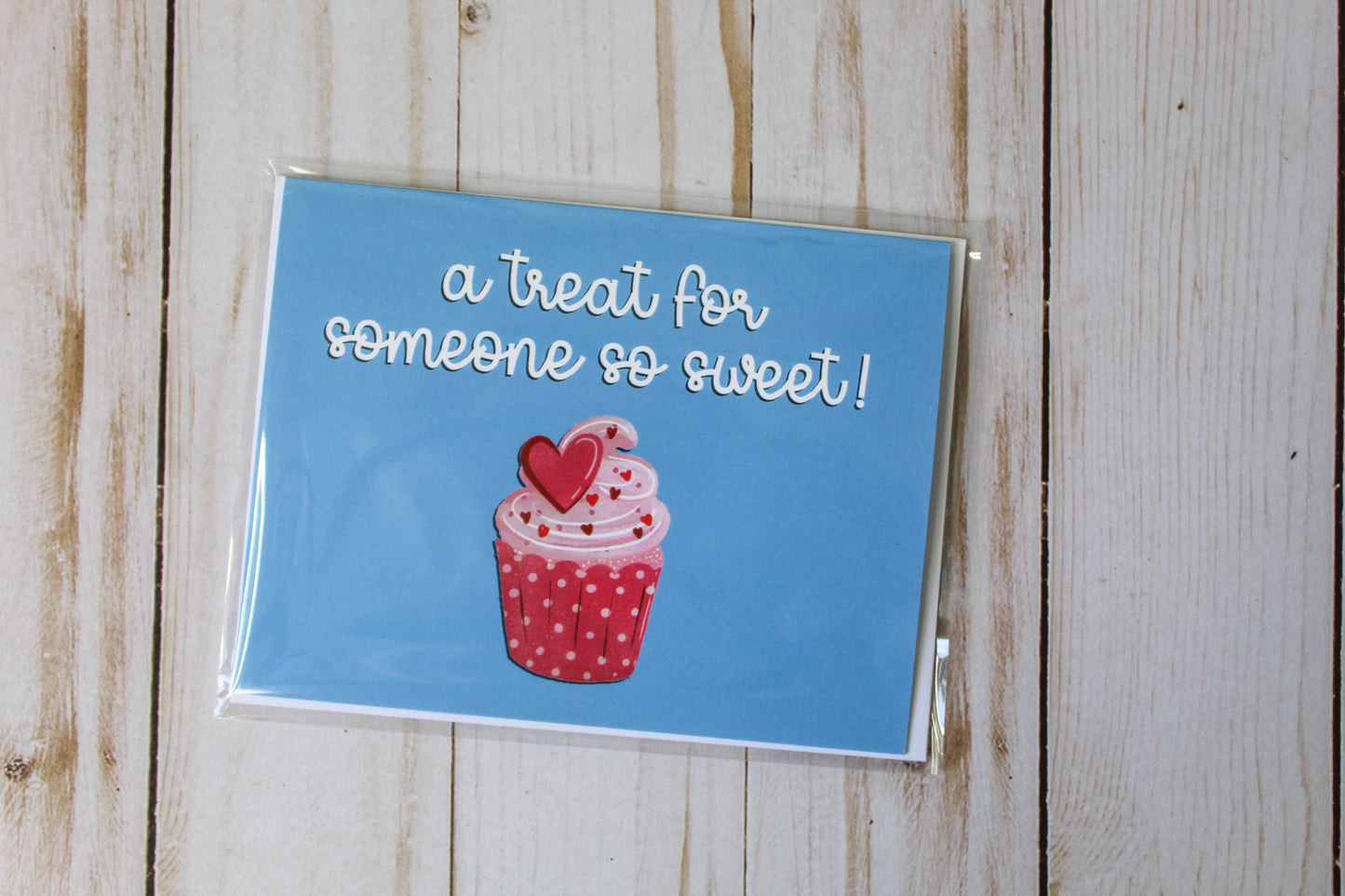 'A Treat For Someone So Sweet' card boasts a charming cupcake design against a blue backdrop. These cards are thoughtfully folded to a size of 4.25" in height by 5.5" in width, leaving the inside blank for your personal message.