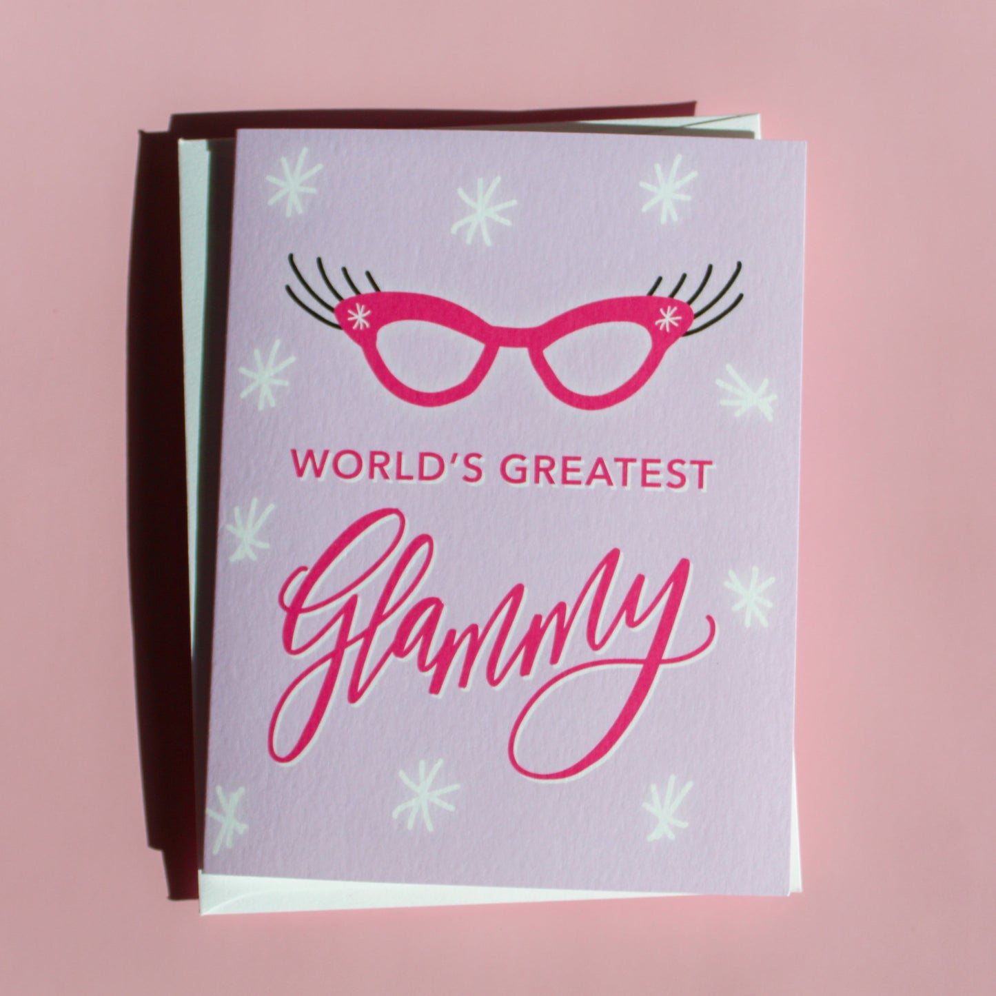 "World's Greatest Glammy" greeting card features hand drawn cat eye glasses with big lashes on a purple background