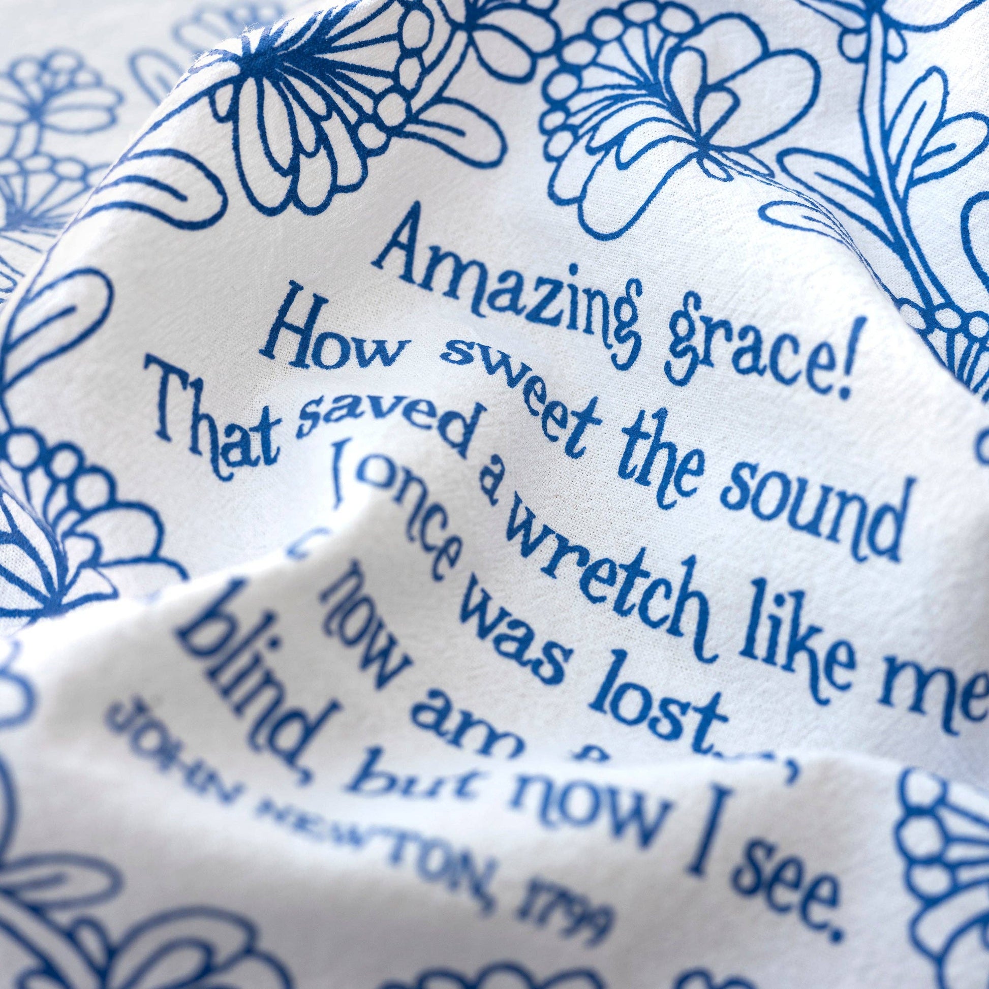 Close-up of hand-lettered Amazing Grace verse on soft white cotton fabric
