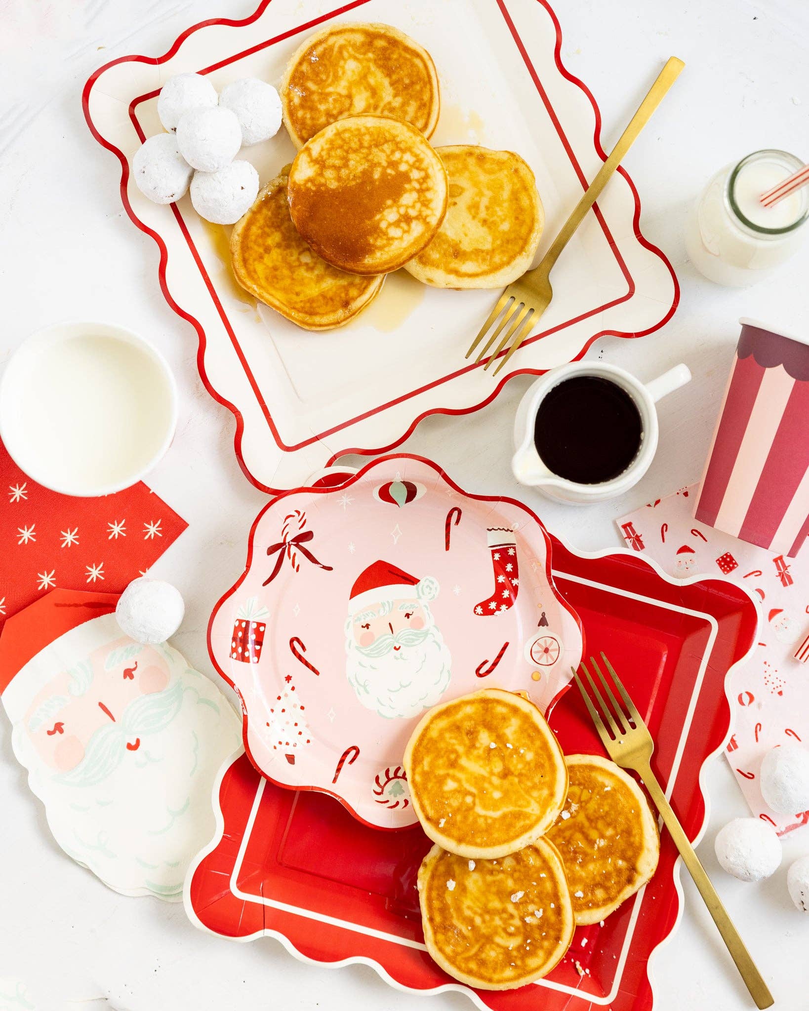 Breakfast setting with pancakes on red and white plates, including a Santa Claus design.
