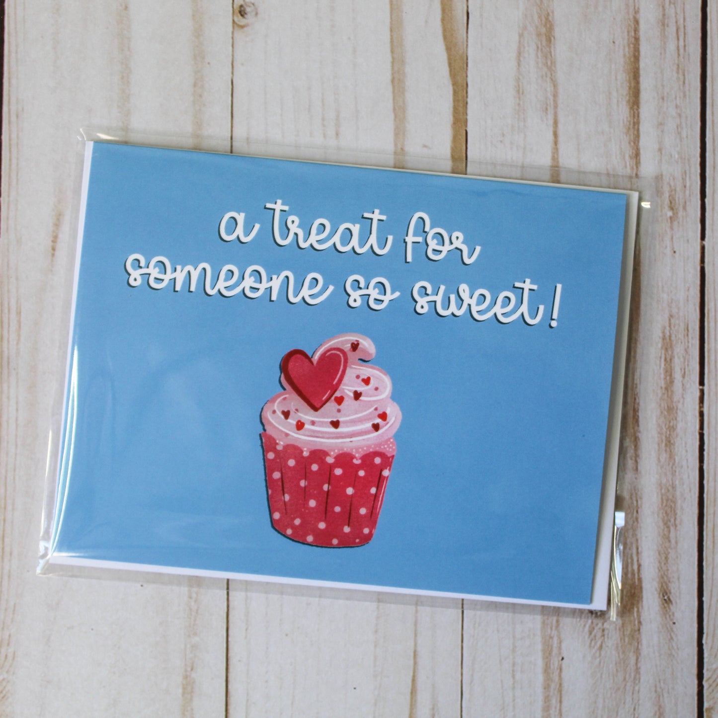 'A Treat For Someone So Sweet' card boasts a charming cupcake design against a blue backdrop. These cards are thoughtfully folded to a size of 4.25" in height by 5.5" in width, leaving the inside blank for your personal message.